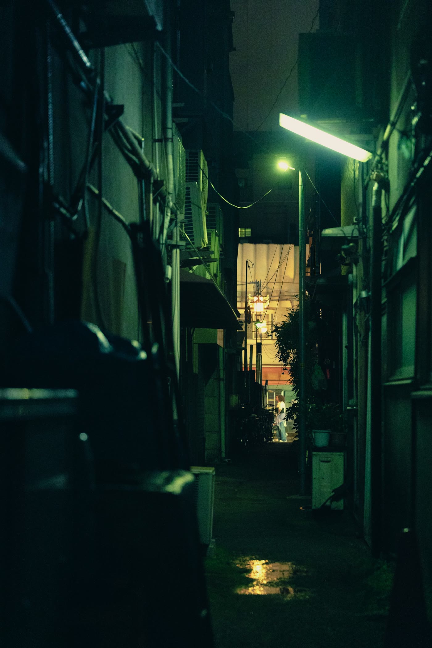 A narrow Tokyo alley at night with warm light